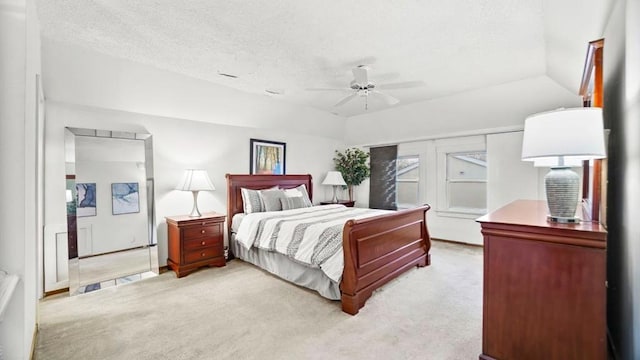 bedroom featuring ceiling fan, light colored carpet, lofted ceiling, and a textured ceiling