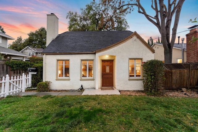 back house at dusk featuring a yard