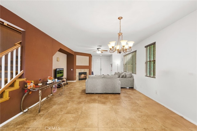 24809 Melrose Dr, Menifee, CA 92585 - living room with a fireplace, stairs, baseboards, tile patterned flooring, and ceiling fan with notable chandelier