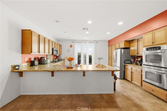 24809 Melrose Dr, Menifee, CA 92585 - kitchen with light stone countertops, stainless steel appliances, a kitchen breakfast bar, visible vents, and a peninsula