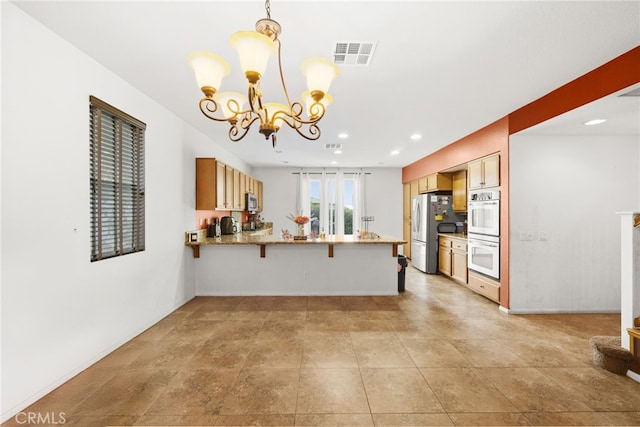 kitchen with a kitchen breakfast bar, appliances with stainless steel finishes, decorative light fixtures, kitchen peninsula, and a chandelier