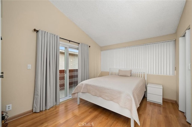 bedroom featuring wood-type flooring, a textured ceiling, access to outside, and lofted ceiling