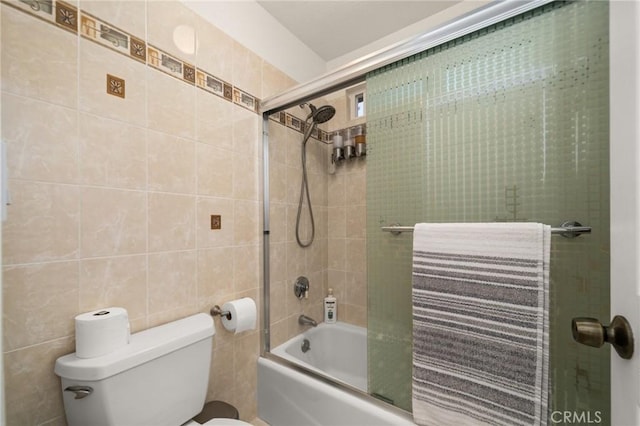 bathroom with toilet, enclosed tub / shower combo, and tile walls