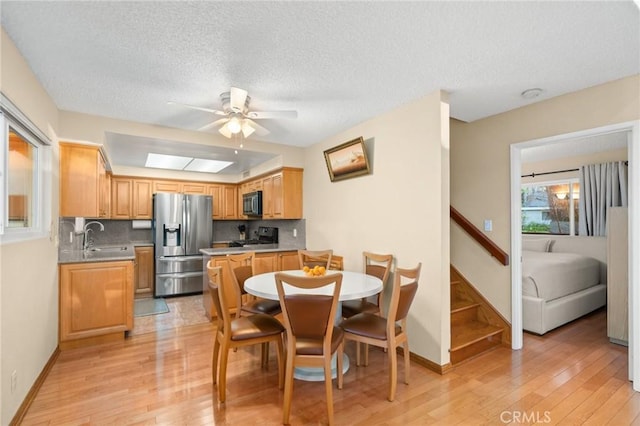 dining space featuring a textured ceiling, light hardwood / wood-style floors, ceiling fan, and sink