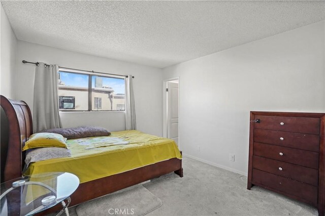 bedroom featuring light colored carpet and a textured ceiling