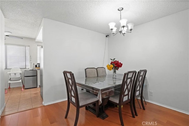 dining area featuring ceiling fan with notable chandelier, a textured ceiling, and hardwood / wood-style flooring