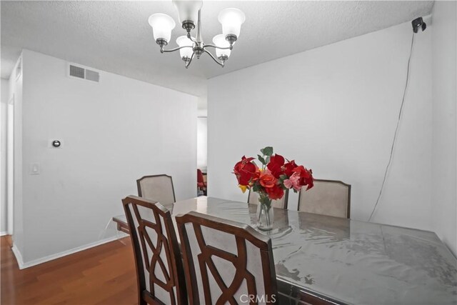 dining room with dark wood-type flooring and a chandelier