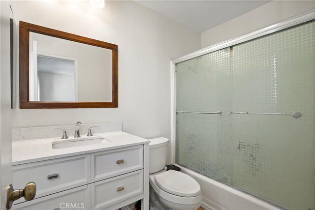 full bathroom featuring toilet, vanity, and shower / bath combination with glass door