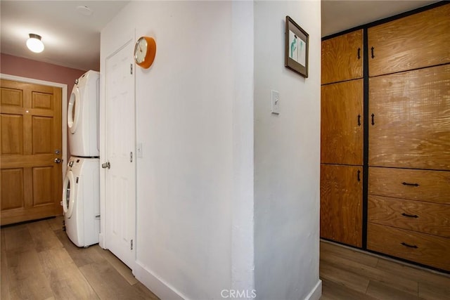 hallway with stacked washer and dryer and light hardwood / wood-style flooring