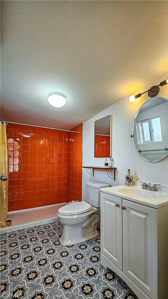 bathroom with a tile shower, vanity, and toilet