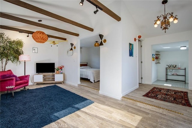 living room with an inviting chandelier, lofted ceiling with beams, and hardwood / wood-style flooring