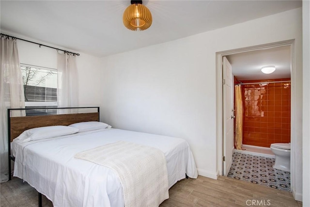 bedroom featuring ensuite bathroom and wood-type flooring