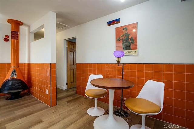 dining space featuring light wood-type flooring and tile walls