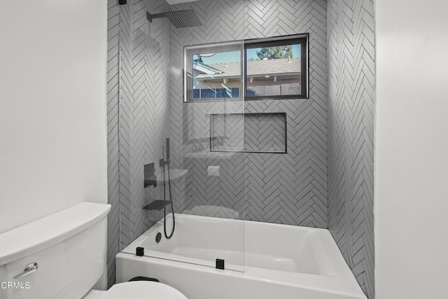 bathroom featuring toilet and tiled shower / bath