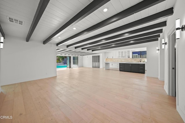 unfurnished living room with light hardwood / wood-style floors, sink, and beam ceiling