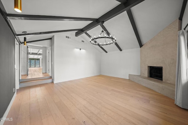 unfurnished living room featuring a large fireplace, light hardwood / wood-style flooring, lofted ceiling with beams, and an inviting chandelier