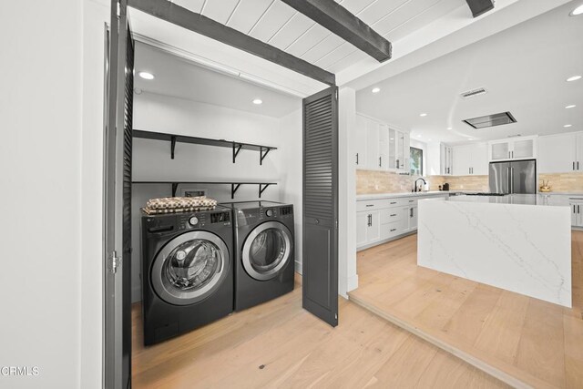 washroom with light hardwood / wood-style floors, sink, and washing machine and clothes dryer