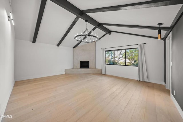 unfurnished living room featuring lofted ceiling with beams, an inviting chandelier, a premium fireplace, and light hardwood / wood-style flooring