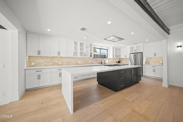 kitchen with a kitchen island, tasteful backsplash, white cabinetry, and light hardwood / wood-style flooring