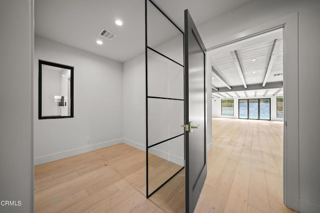 hallway featuring beamed ceiling and light hardwood / wood-style flooring