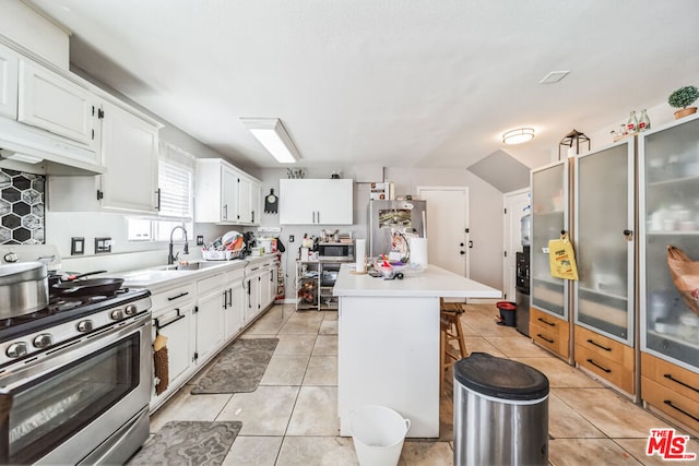 kitchen featuring a center island, sink, stainless steel appliances, a kitchen breakfast bar, and white cabinets