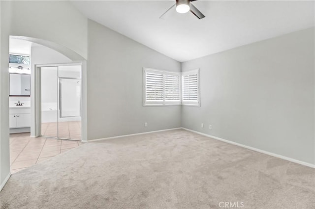 carpeted empty room featuring ceiling fan, sink, and vaulted ceiling