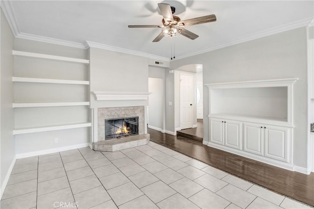 unfurnished living room with a tile fireplace, light hardwood / wood-style flooring, and crown molding