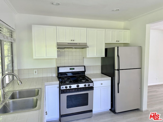 kitchen with stainless steel fridge, gas range oven, sink, light hardwood / wood-style flooring, and white cabinetry