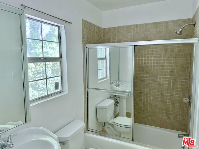 full bathroom with sink, toilet, and bath / shower combo with glass door