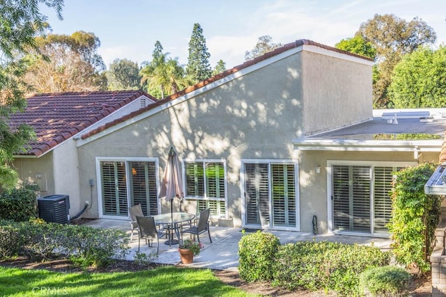 back of property with central AC and a patio