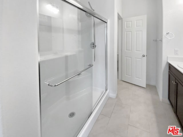 bathroom featuring tile patterned floors, vanity, and a shower with shower door