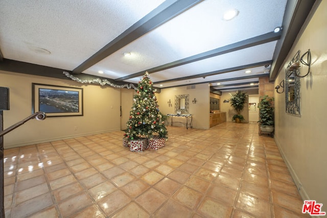 interior space featuring light tile patterned floors, beamed ceiling, and a textured ceiling