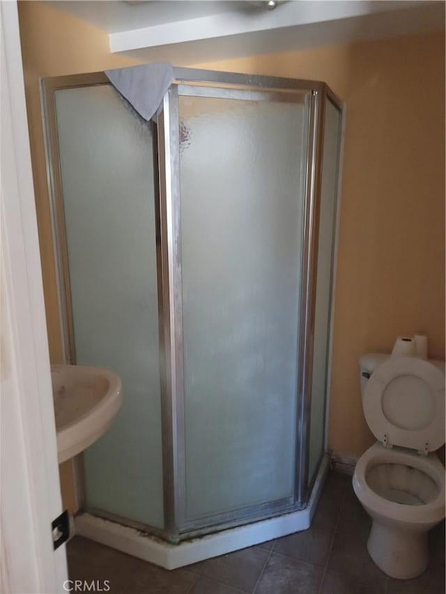 bathroom with tile patterned floors, a shower with door, and toilet