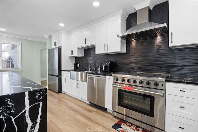 kitchen with white cabinets, decorative backsplash, wall chimney range hood, and stainless steel appliances