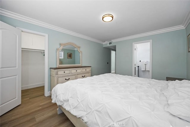 bedroom with hardwood / wood-style floors, a spacious closet, crown molding, and a closet