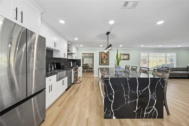 kitchen with a breakfast bar area, stainless steel fridge, white cabinetry, and a kitchen island