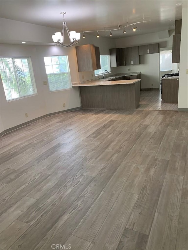 kitchen with kitchen peninsula, sink, light hardwood / wood-style flooring, and an inviting chandelier