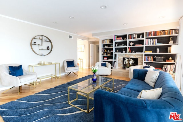 living room featuring a tile fireplace, wood-type flooring, and crown molding