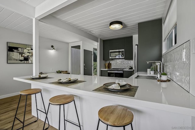 kitchen featuring sink, kitchen peninsula, stainless steel appliances, and a breakfast bar