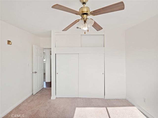 unfurnished bedroom with ceiling fan, a closet, and light carpet