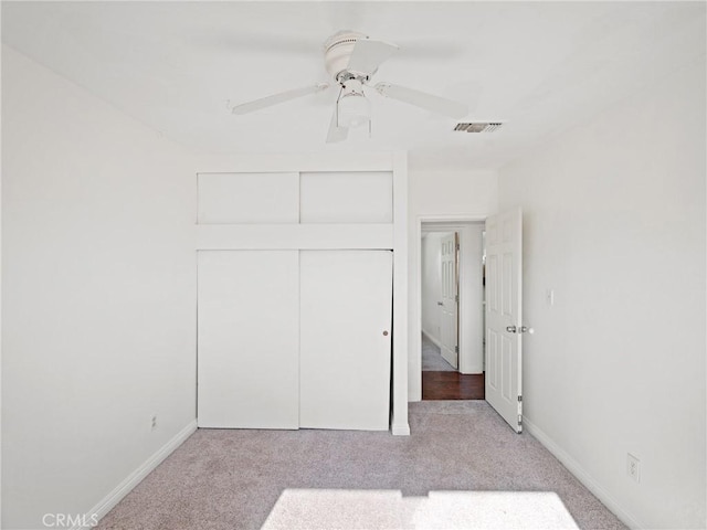 unfurnished bedroom featuring ceiling fan, a closet, and light colored carpet