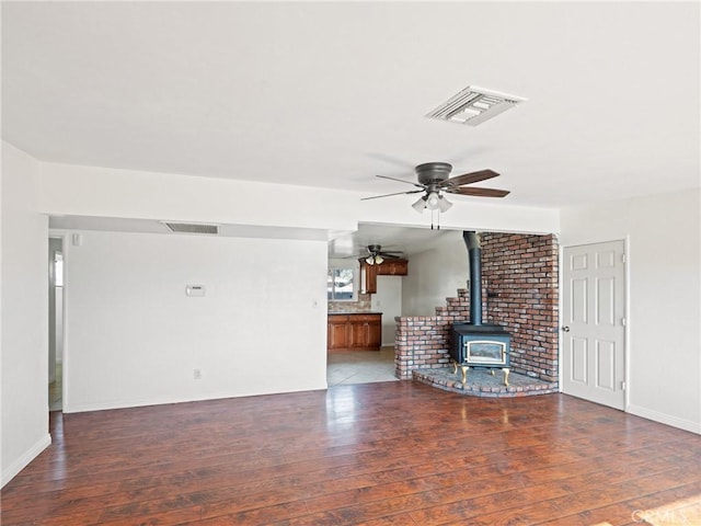 unfurnished living room featuring a wood stove and dark wood-type flooring