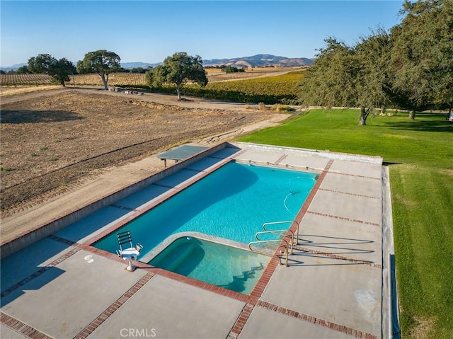 view of swimming pool with a mountain view, a yard, a rural view, and a diving board