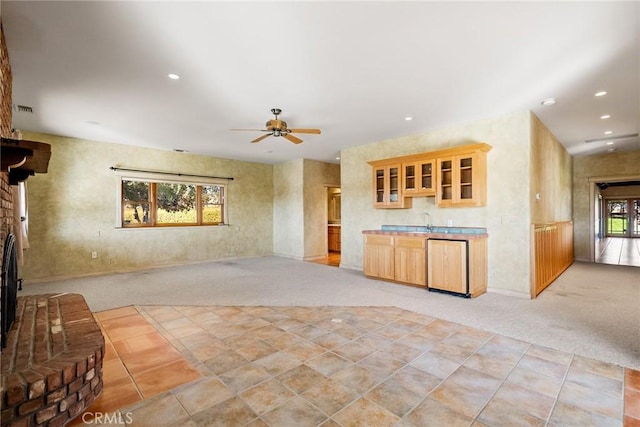 kitchen with ceiling fan, light colored carpet, and a brick fireplace