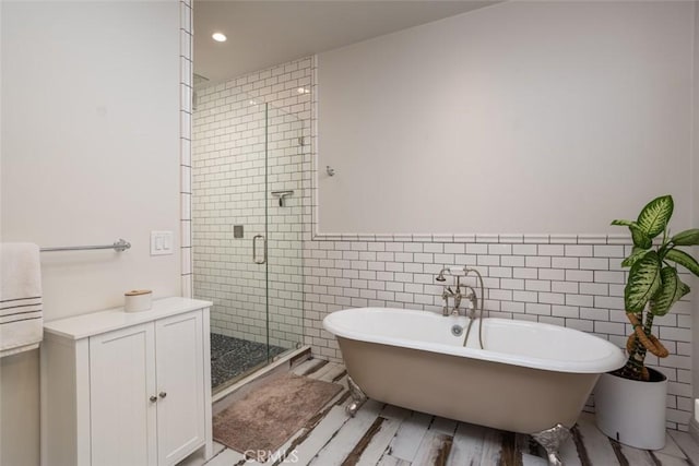 bathroom featuring tile walls and independent shower and bath