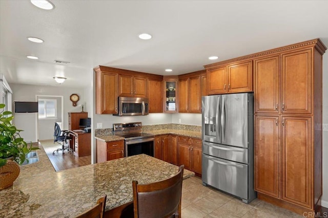 kitchen with kitchen peninsula, light stone counters, a breakfast bar, and stainless steel appliances