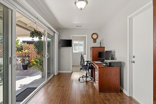 home office with a wealth of natural light and dark hardwood / wood-style flooring