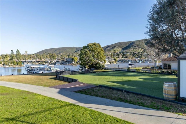 view of property's community featuring a lawn and a water and mountain view