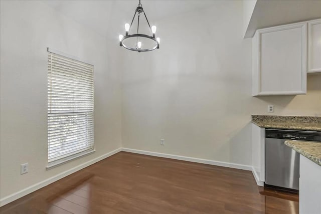 unfurnished dining area with dark hardwood / wood-style flooring and an inviting chandelier