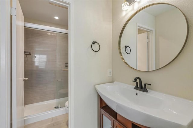 bathroom featuring vanity, a shower with shower door, and toilet